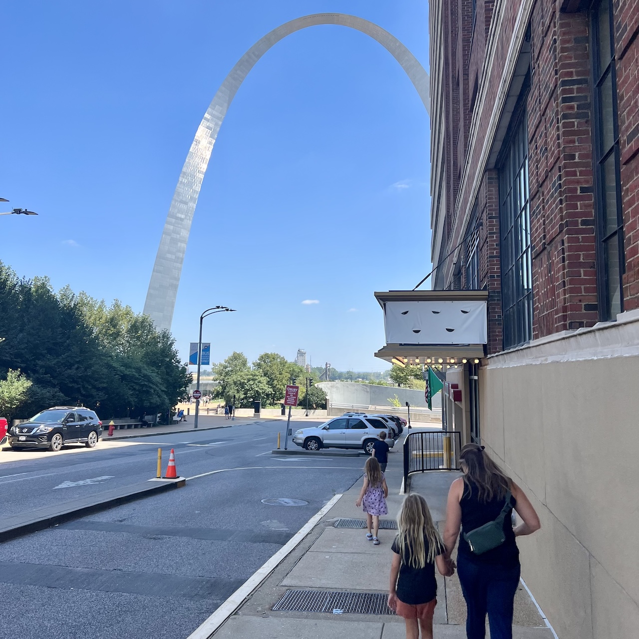 Humans walking towards a silver arch.